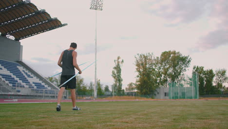 Lanzador-De-Jabalina-Cansado,-Un-Hombre-En-El-Estadio-Recoge-Lanzas.-Preparándose-Para-Todo.-Caminando-Por-El-Estadio-Después-Del-Entrenamiento-Al-Fondo-De-Las-Gradas-Y-Portando-Lanzas-Para-Lanzar.